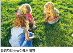 세 여자 아이가 풀밭에 쪼그리고 앉아 놀고 있는 사진