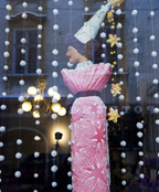 쇼윈도에 걸려 있는 꼬깔 모자를 쓰고 자수옷을 입은 인형을 촬영한 모습입니다.